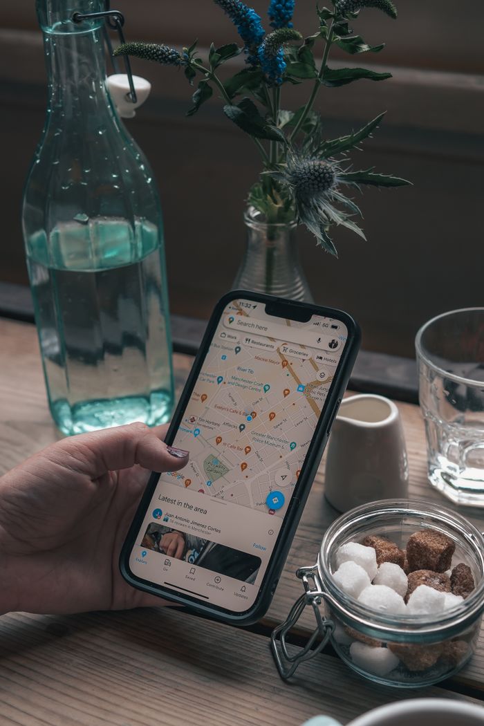 A smartphone with a map app in a cozy café setting, ideal for travel and technology themes.